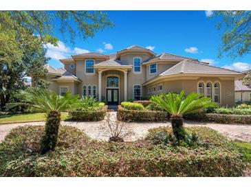 Two-story house with tile roof, landscaping, and a long driveway at 10527 Emerald Chase Dr, Orlando, FL 32836