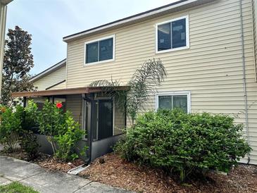 Tan two-story condo with covered patio, landscaping, and mature shrubs at 1123 Spring Meadow Dr # 1123, Kissimmee, FL 34741