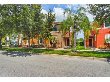 Two-story tan and orange house with palm trees and a grassy yard at 491 Las Fuentes Dr, Kissimmee, FL 34746