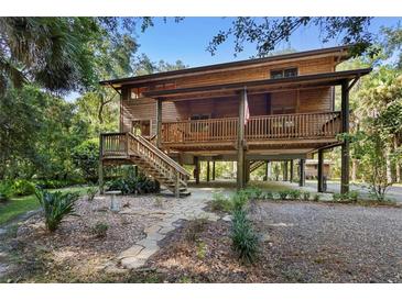 Rustic two-story home on stilts with a wooden exterior and large deck at 1205 Sutton Trl, Geneva, FL 32732