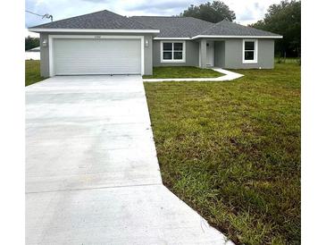 Newly built single story house with a two-car garage and driveway at 12202 Se 87Th Ct, Belleview, FL 34420