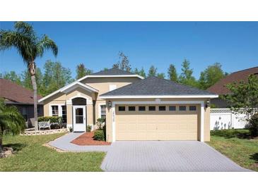 Tan one-story house with gray roof, two-car garage, and landscaped yard at 2635 Quarterdeck Ct, Kissimmee, FL 34743