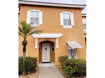 Two story townhome with stucco exterior and walkway at 1107 Park Ridge Cir, Kissimmee, FL 34746