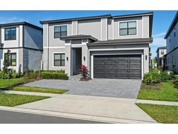 Two-story home with gray exterior, black garage door, and landscaping at 5936 High Seas Dr, Orlando, FL 32821