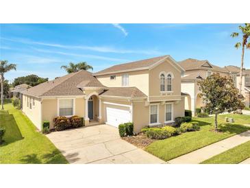 Two-story house with a tan exterior, a two-car garage, and well-maintained landscaping at 511 Pineloch Dr, Haines City, FL 33844