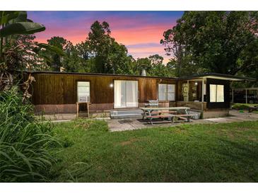 Single-wide mobile home with a covered patio and picnic table, nestled in a wooded area at 1099 Bee Ln, Geneva, FL 32732