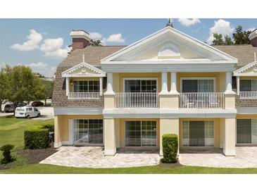 Two-story home with a balcony, columns, and a landscaped yard at 7509 Seven Eagles Way, Reunion, FL 34747