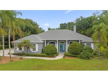 Two-story house with gray siding, teal door, and manicured landscaping at 12908 Creekside Ct, Clermont, FL 34711