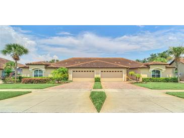 Tan two-story home with double garage and manicured lawn at 26841 Bella Vista Dr, Howey In The Hills, FL 34737