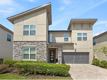 Two-story modern home with stone accents and a three-car garage at 8975 Amelia Downs Trl, Kissimmee, FL 34747