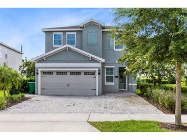 Two-story house with gray siding, shutters, and a paver driveway at 7443 Marker Ave, Kissimmee, FL 34747