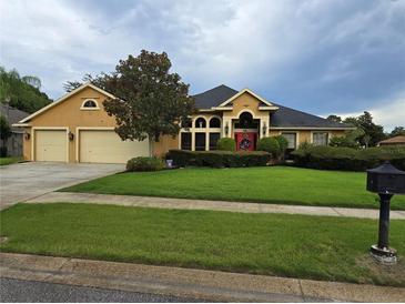 Two-story house with yellow exterior, three-car garage and lush landscaping at 531 Soft Shadow Ln, Debary, FL 32713