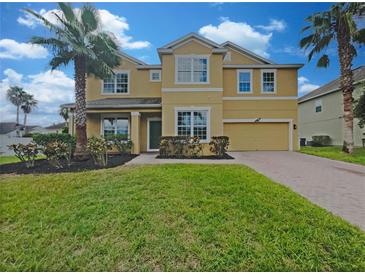 Two-story house with a yellow facade, palm trees, and a brick driveway at 15106 Ovation Dr, Winter Garden, FL 34787