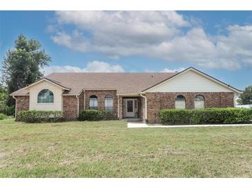 Brick ranch house with a brown roof, landscaping, and a spacious yard at 613 Tradewinds Dr, Deltona, FL 32738