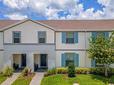 Front view of a two-story townhouse with gray and white siding, blue shutters, and a landscaped lawn at 2408 Dubai St, Kissimmee, FL 34747