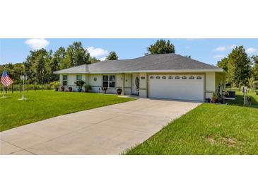 Single-story home with a two-car garage and a well-maintained lawn at 10604 Se 146Th Ln, Summerfield, FL 34491