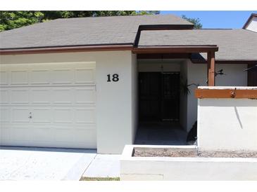 Condo exterior with a white garage door and landscaping at 2681 Washington Ave # 18, Eustis, FL 32726