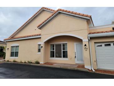 Tan house with arched entryway, two windows, and attached garage at 332 David Walker Dr # J-2, Tavares, FL 32778