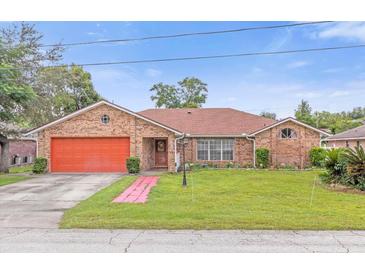 Brick ranch home with a large front yard and orange garage door at 897 Vicksburg St, Deltona, FL 32725
