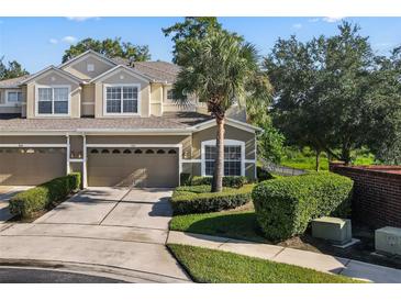Tan two-story townhome with two-car garage, lush landscaping, and a palm tree at 400 Harbor Winds Ct, Winter Springs, FL 32708
