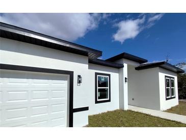 Modern house exterior with white walls, black accents, and a two-car garage at 609 Amazon Pl, Kissimmee, FL 34759