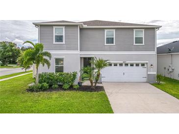 Two-story house with gray siding, white garage door, and landscaping at 14007 Creek Harbor Dr, Orlando, FL 32824