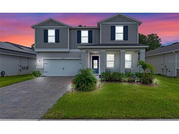 Two-story house with gray siding, white garage door, and landscaped yard at 2864 Sanctuary Dr, Clermont, FL 34714