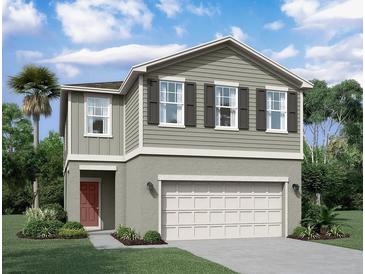Two story home with two tone exterior, two car garage, and red door at 1955 Hemingway Cir, Groveland, FL 34736