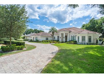 Luxury home with a circular driveway, manicured lawn, and Mediterranean style at 5056 Isleworth Country Club Dr, Windermere, FL 34786