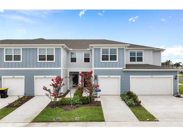 Two-story townhome with blue siding, attached garages, and landscaping at 2614 Winsome Way, Davenport, FL 33896