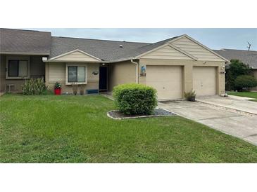 Tan brick exterior home with a two-car garage and well-manicured lawn at 5027 Se 109Th Pl, Belleview, FL 34420
