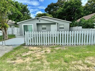 Updated bungalow with gray exterior, white picket fence, and a paved driveway at 117 N Observatory Dr, Orlando, FL 32835