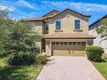 Two-story home with a tan facade and brick paver driveway at 1471 Rolling Fairway Dr, Davenport, FL 33896