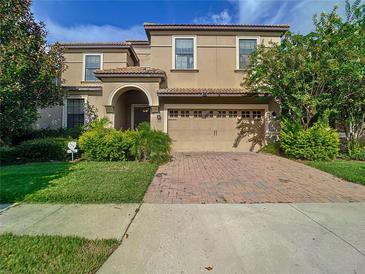 Two-story house with tan exterior, three-car garage, and landscaped yard at 1410 Wexford Way, Davenport, FL 33896