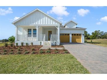 Charming farmhouse style home with a spacious covered porch and attached two-car garage at 487 Toscano St, Clermont, FL 34715