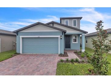 Two-story house with light blue garage door and brick driveway at 3793 Bluethread Way, Poinciana, FL 34759