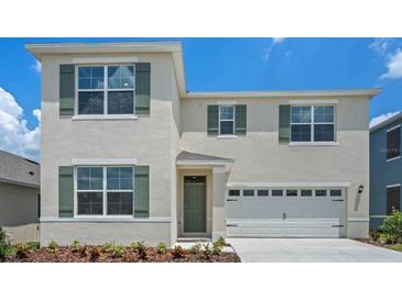 Two-story home with light beige siding, green shutters, and a two-car garage at 3540 Broadwing Blvd, Poinciana, FL 34759
