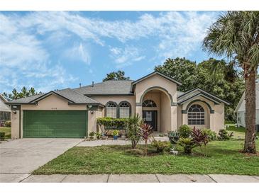 Tan one-story house with green garage door and landscaped yard at 16208 Magnolia Hill St, Clermont, FL 34714