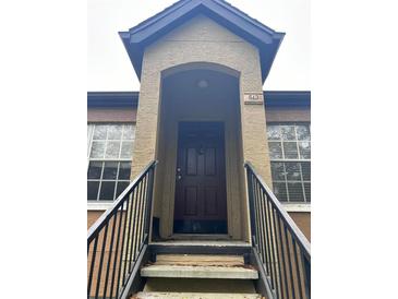 Exterior view of condo building entrance with stairs and brown door at 6312 Raleigh St # 513, Orlando, FL 32835