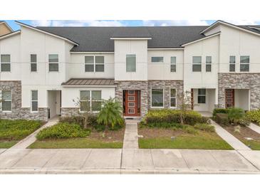 Modern townhome exterior with stone and white siding, and a red door at 2163 Copper Bell Pl, Kissimmee, FL 34747