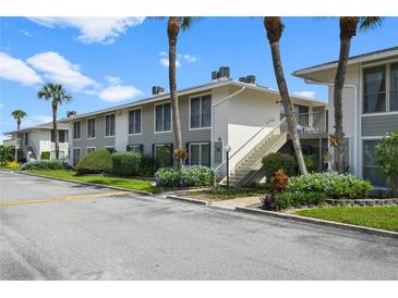 Condo building with gray siding, lush landscaping, and stairs at 1935 Conway Rd # M3, Orlando, FL 32812