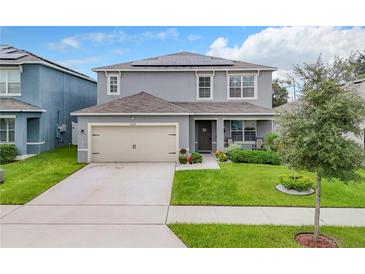 Two-story house with gray siding, solar panels, and a two-car garage at 1526 White Hawk Way, Groveland, FL 34736