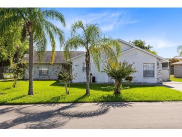 One-story home with white exterior, lush lawn, and palm trees at 148 Merida Dr, Kissimmee, FL 34743