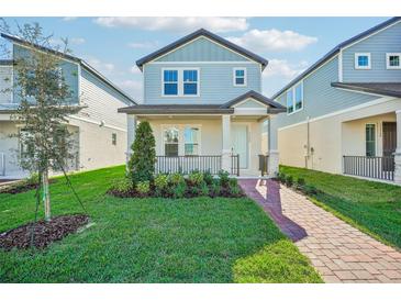 Two-story light blue house with brick walkway, landscaping, and a front porch at 11960 Bracco St, Winter Garden, FL 34787