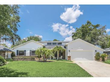 White house with a brick facade, two-car garage and palm trees at 7904 Dunstable Cir, Orlando, FL 32817