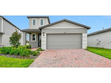 Two-story house with gray siding, brick paver driveway, and landscaping at 3669 Portsmouth Ln, Haines City, FL 33844