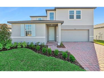 Two-story house with gray siding, brick driveway, and landscaping at 2462 Leeds St, Haines City, FL 33844