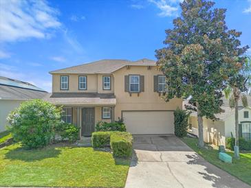 Two-story house with beige exterior, brown accents, and a two-car garage at 525 Aster Dr, Davenport, FL 33897