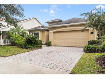 Tan one-story house with a two-car garage and well-maintained landscaping at 1381 Hazeldene Mnr, Deland, FL 32724