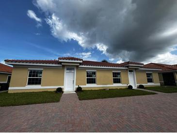 Three-unit building with red tile roofs, yellow siding, and brick driveways at 1648 Cumin Dr, Kissimmee, FL 34759